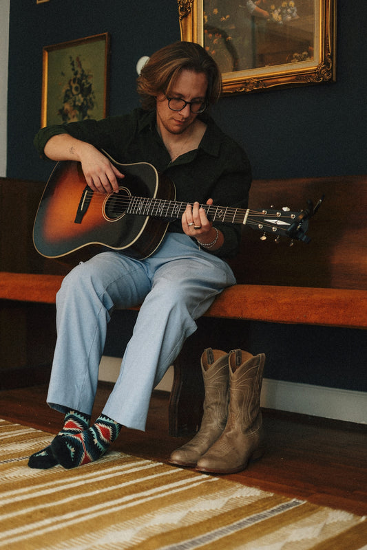 A person sitting on a bench playing a guitar