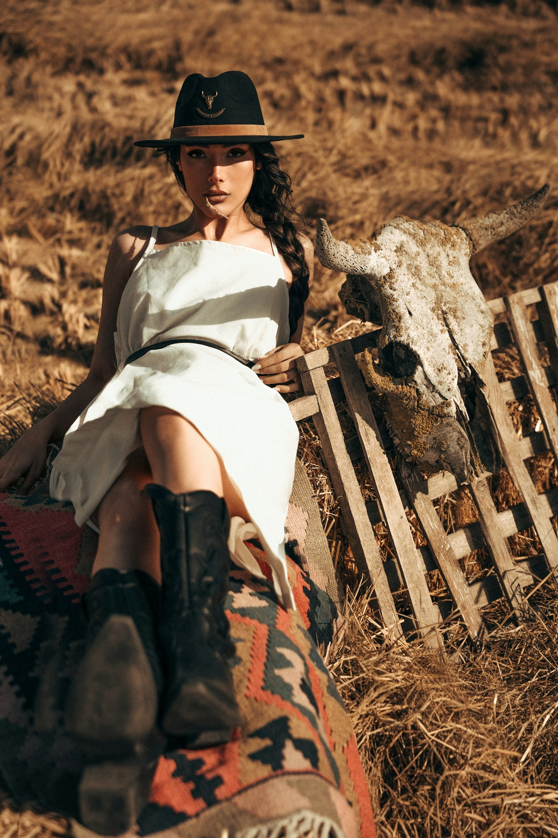 Woman in cowboy hat and boots with cow skull.