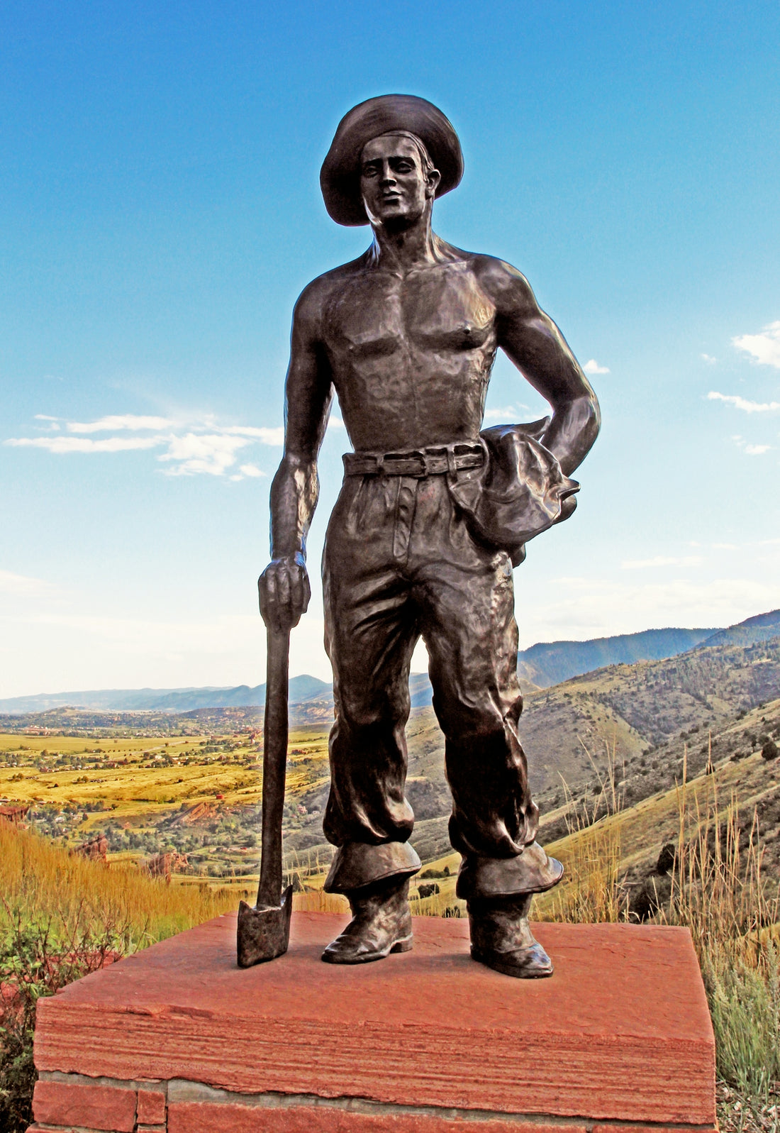 Bronze statue of a man with shovel and hat.