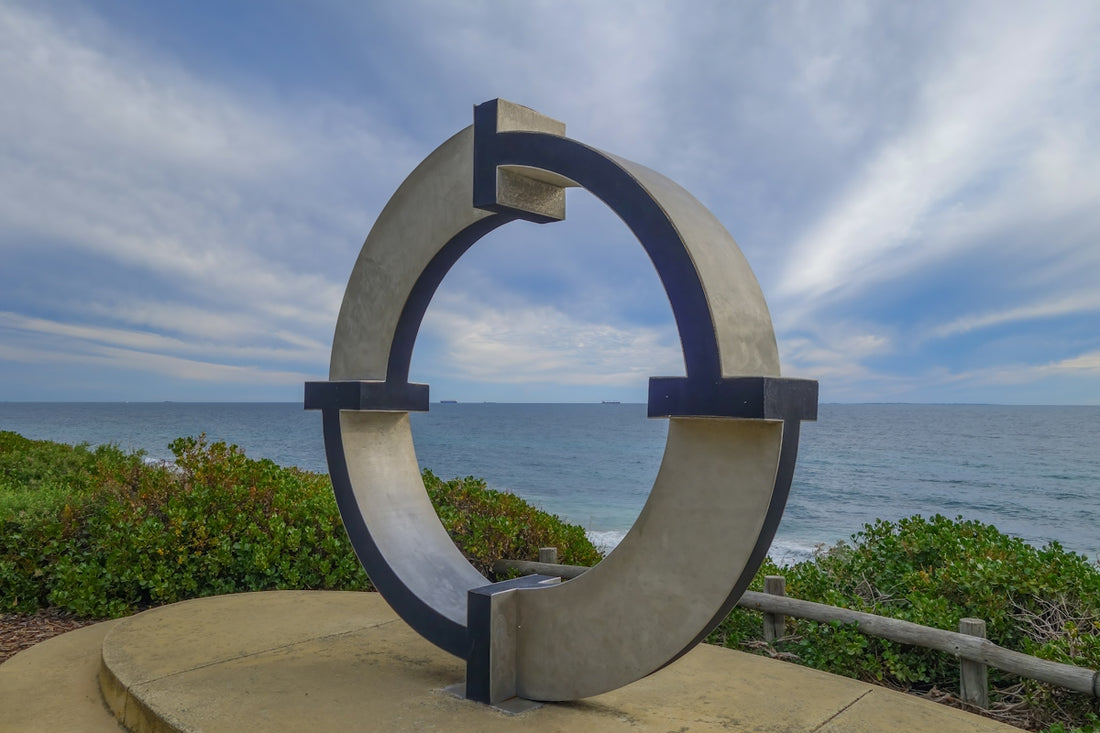 Modern circular sculpture overlooking the vast blue ocean.